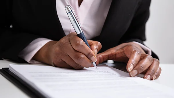 Business Woman signing paperwork with a pen, hand shot